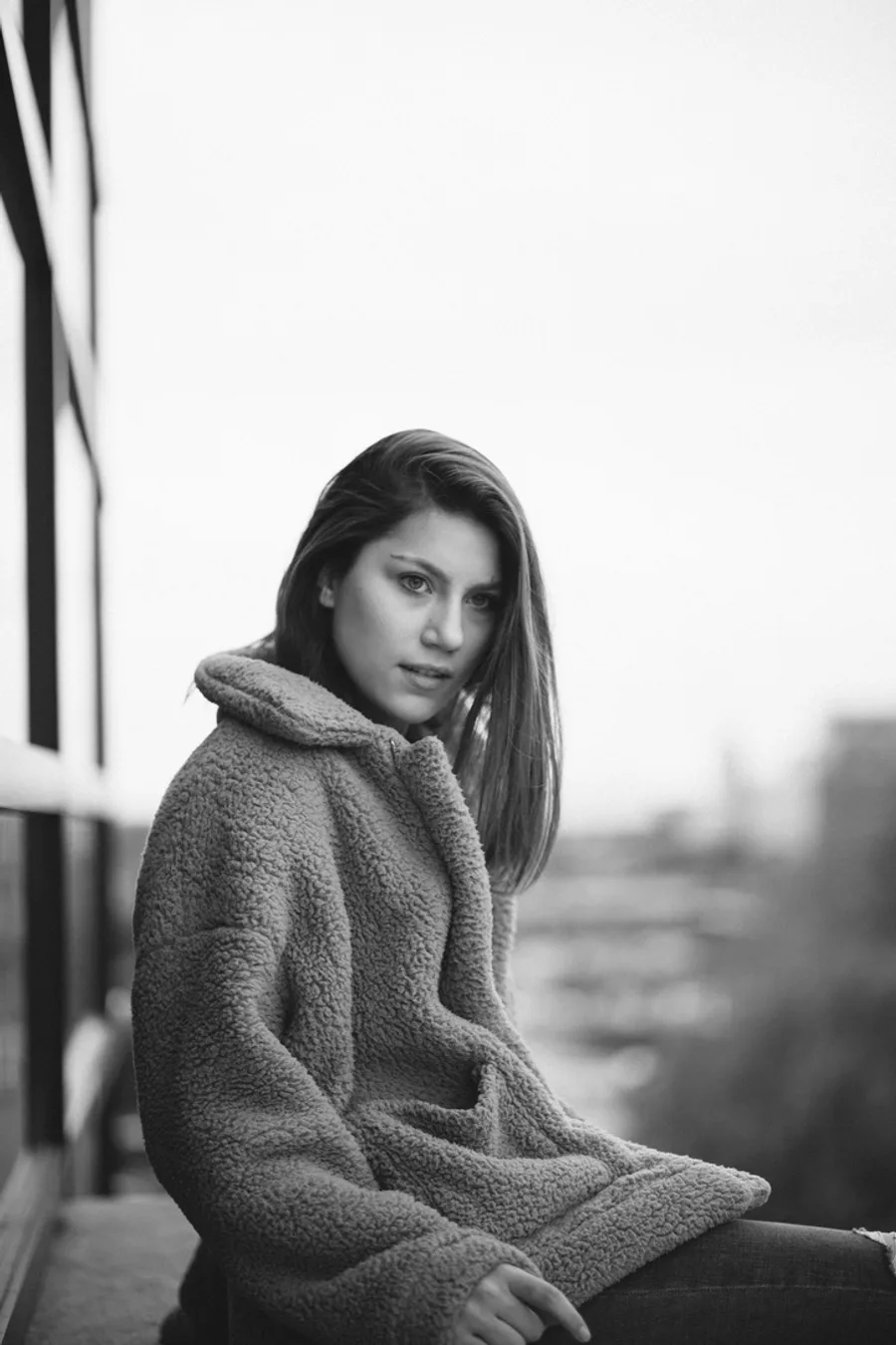 Black and white portrait of a woman in a sherpa coat on a rooftop