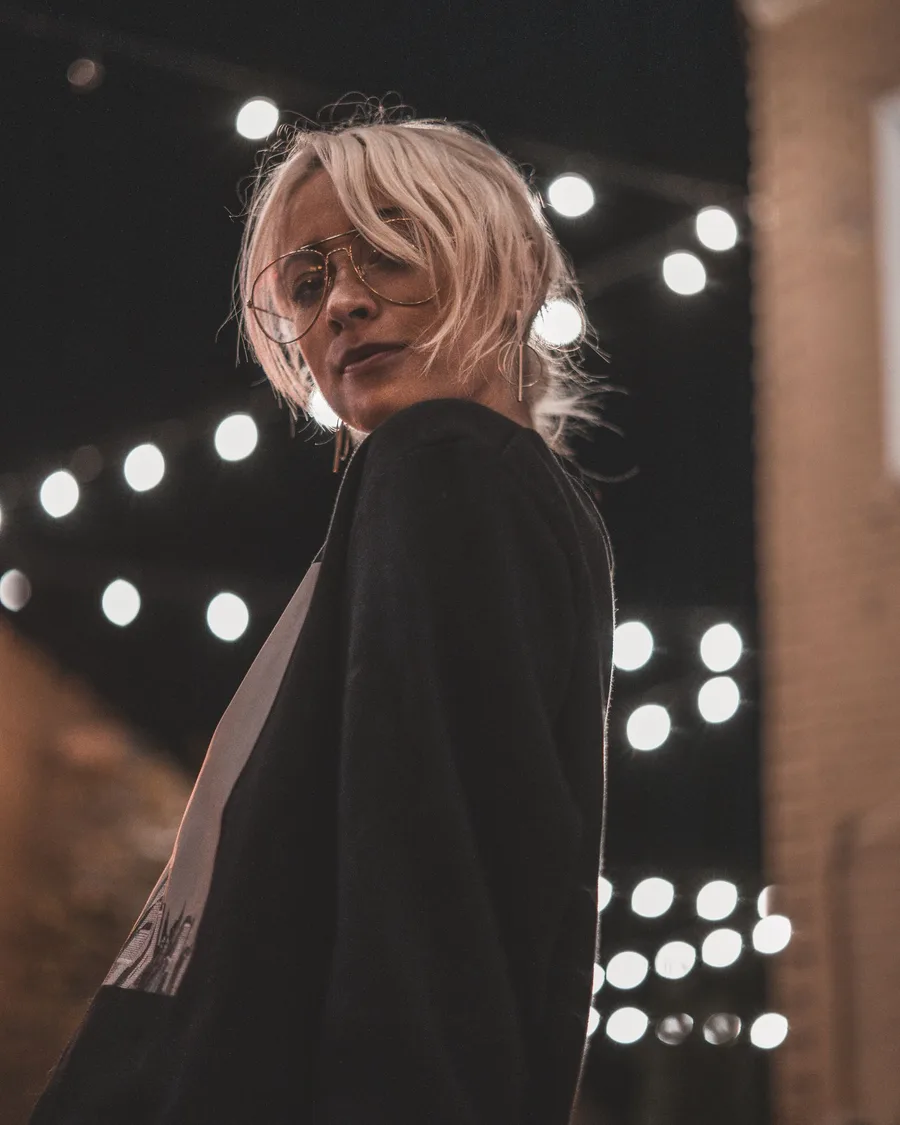 Night portrait of a woman in glasses under string lights