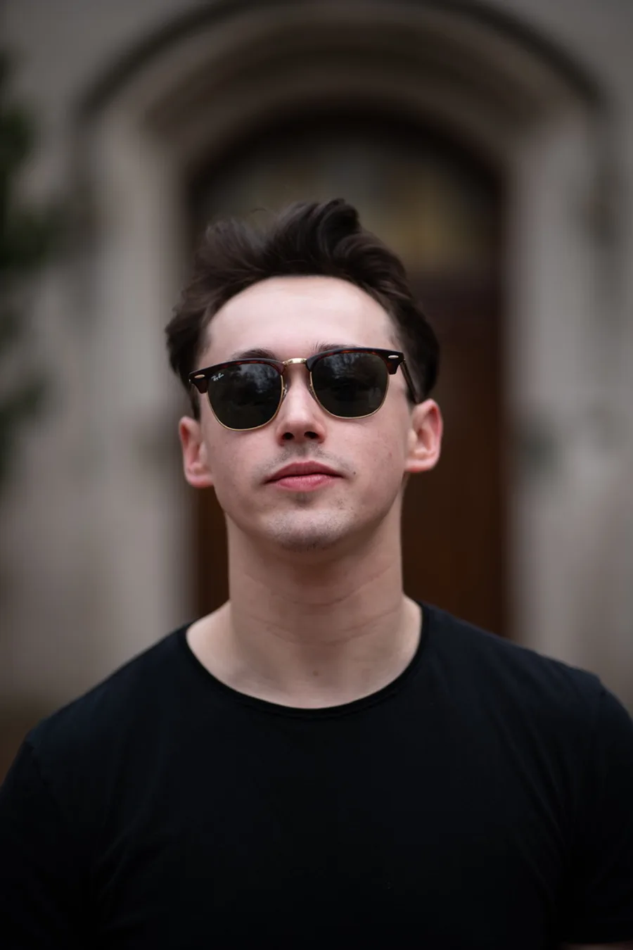 Portrait of a man in sunglasses in front of an arched doorway