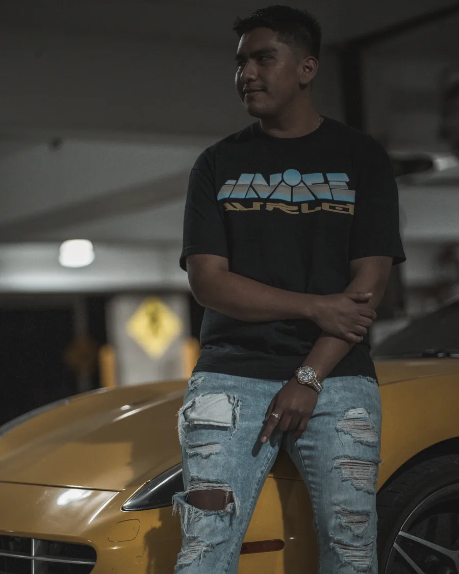 Portrait of a man leaning on a yellow sports car in a parking garage